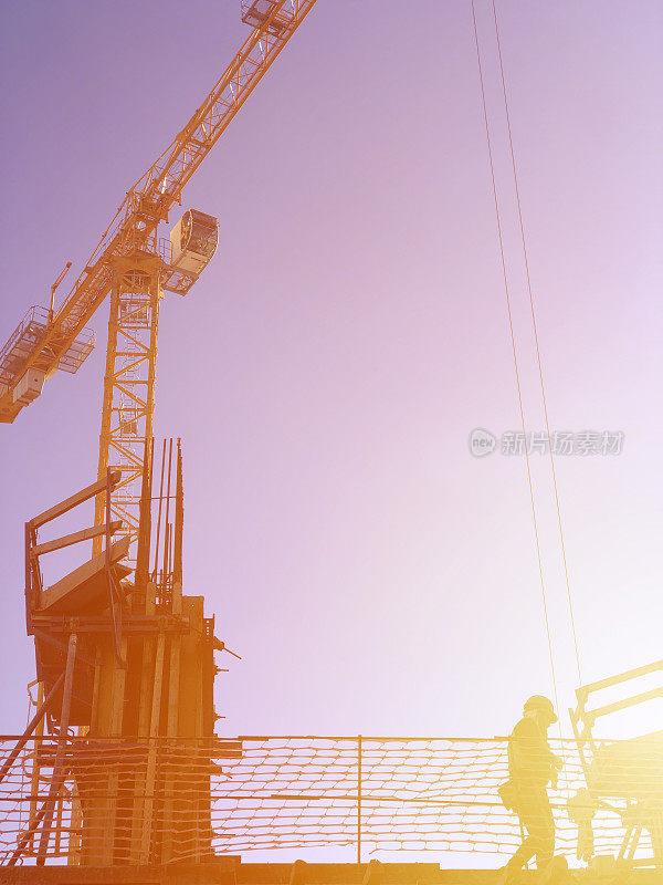 日出时工业建筑起重机和建筑物剪影