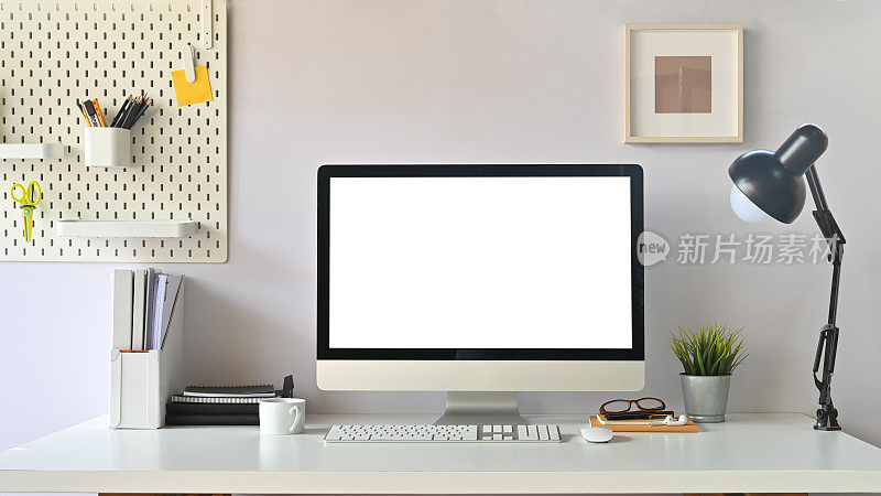 创意工作空间的正面视图。办公室办公桌上的白色黑屏电脑。设备表。