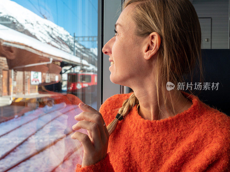 在瑞士乘火车旅行的年轻女子透过窗户看