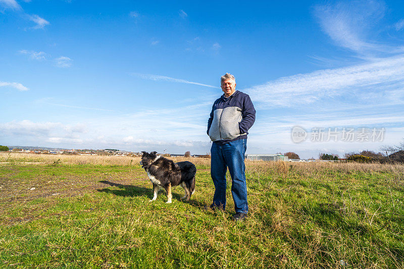 一名男子和边境牧羊犬在草原上散步