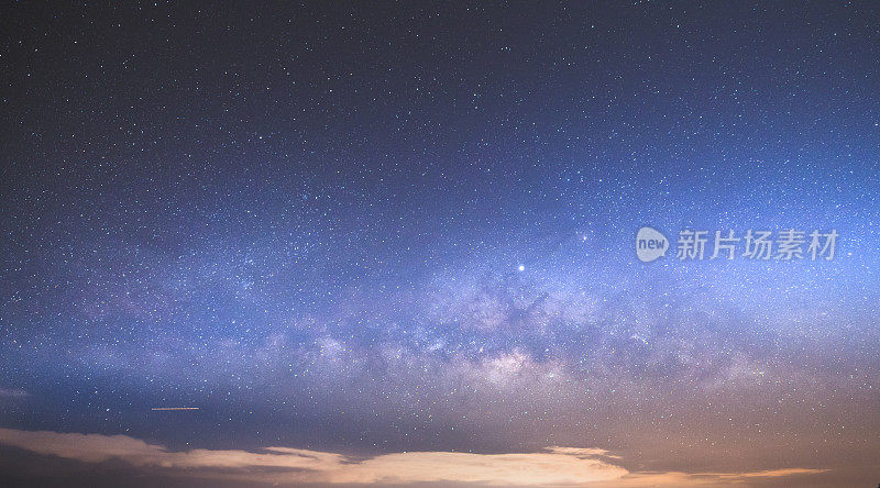 山上有银河和粉红的光。晚上多彩的景观。夏天的星空和山峦。美丽的宇宙。太空背景与星系。旅游的背景