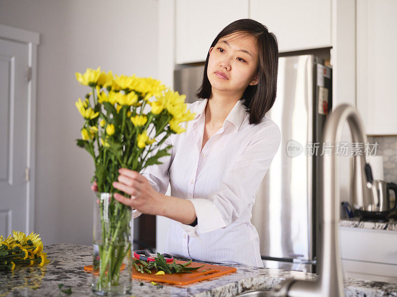 亚洲妇女在她的家里插花