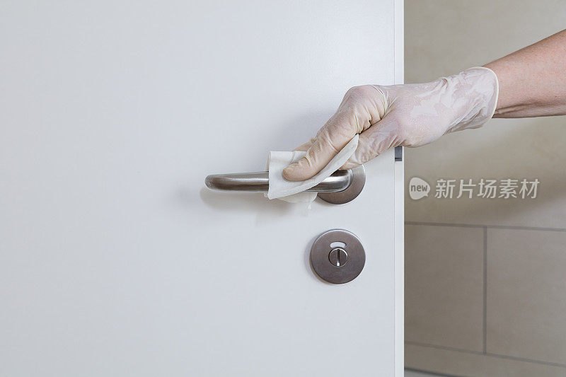 女工人用抗菌消毒擦拭布清洁门把手
