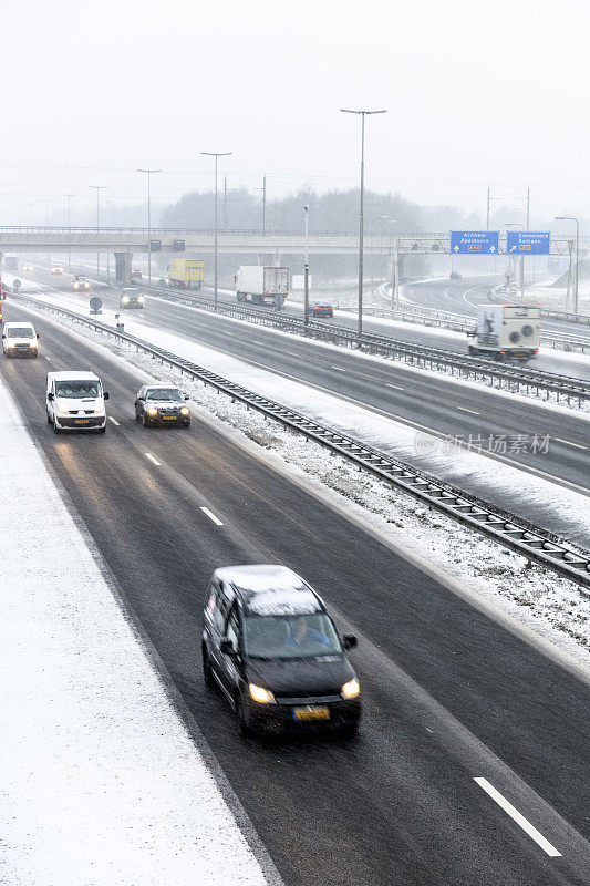 在冬季暴风雪期间，在多条车道的高速公路上行驶的车辆
