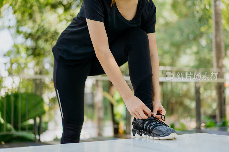 年轻的亚洲女人系她的鞋带，准备跑