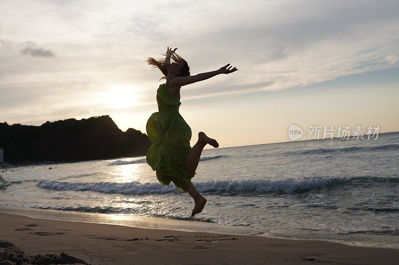 快乐的女人拿着帽子跑着跳着尽情享受海滩度假的生活。