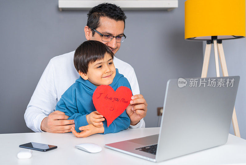 父亲和儿子通过电脑视频聊天应用与母亲在母亲节。母亲节的庆祝活动。母亲节快乐