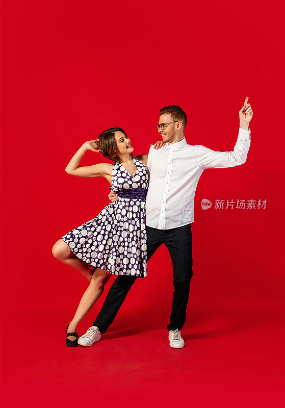 老式时尚的年轻夫妇在红色背景上跳舞