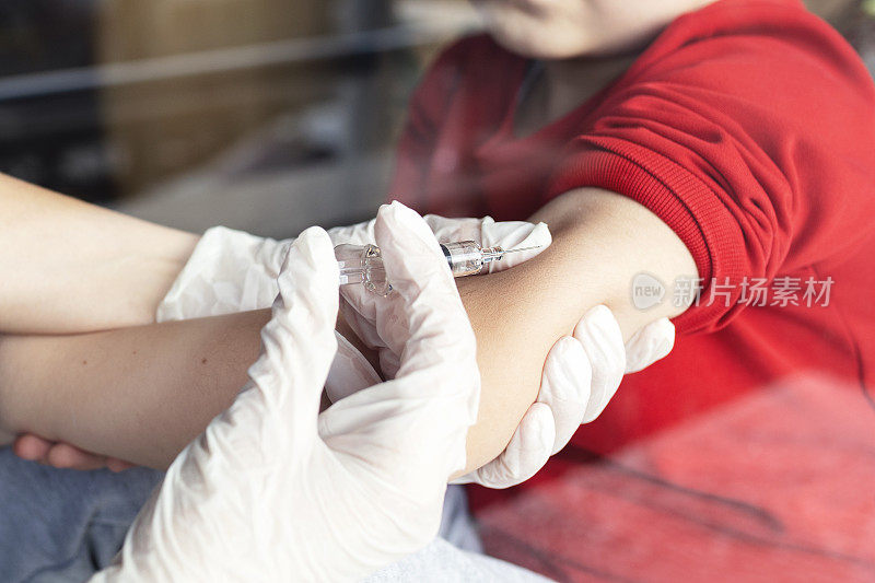 女医生戴着乳胶手套，用装有新冠疫苗的针头和注射器给一名儿童注射疫苗