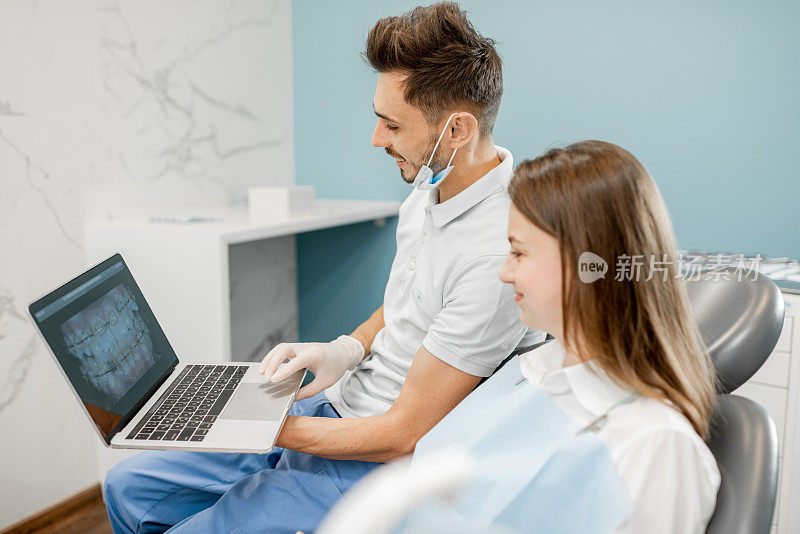 牙医在一个年轻病人的监视器上显示牙齿的照片