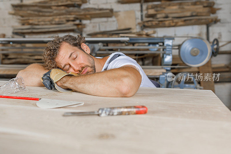 非常疲惫的木匠正在从一个车间的辛苦工作中休息。