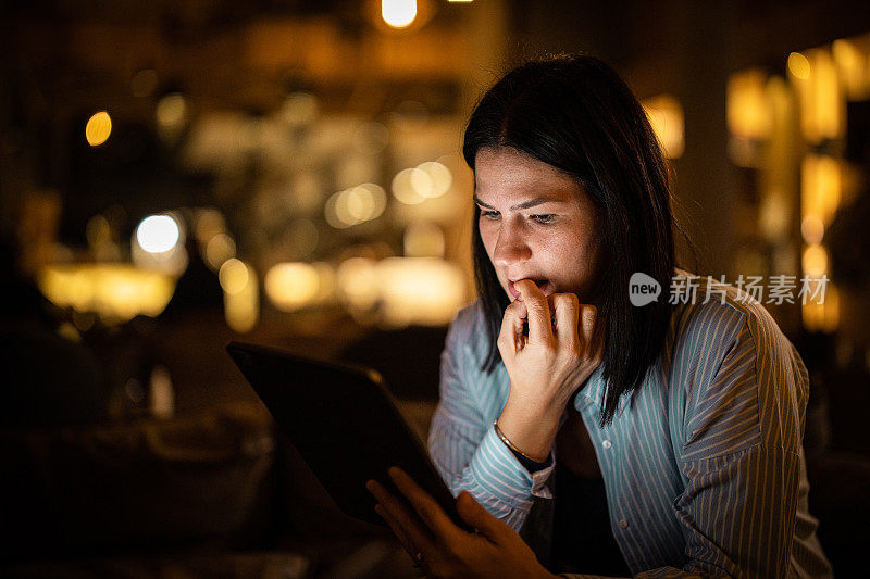 穿着考究的女人坐在餐厅里用平板电脑看新闻