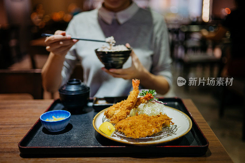 年轻女子在餐馆吃日本猪排饭