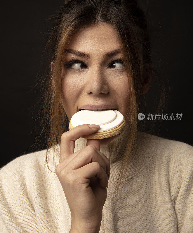 一个年轻女子在吃饼干的时候快乐地对眼。