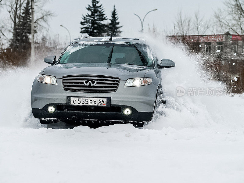 汽车英菲尼迪QX70，冬天开车穿过雪堆时的汽车照片。