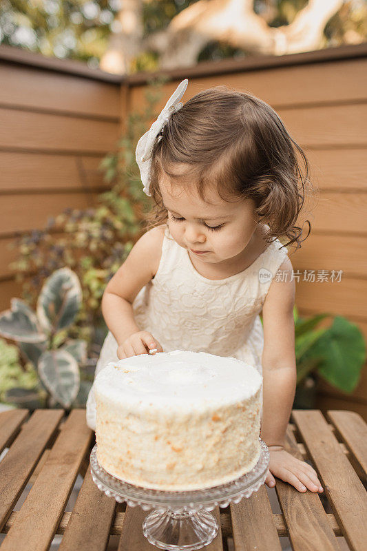 新冠肺炎期间，小女孩在家的2岁生日派对上吃着简单的白奶油生日蛋糕