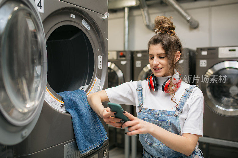 一个年轻的白人女人在自助洗衣店洗衣服