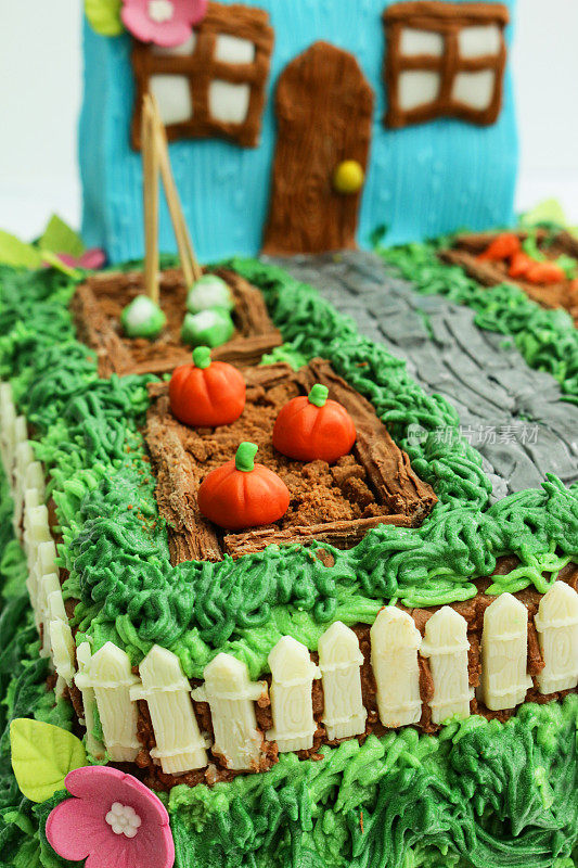 形象的自制蛋糕设计为小屋和花园，黄油糖霜草和方糖糖霜通道，巧克力片种植的饼干屑土壤，方糖糖霜花椰菜和南瓜细节，聚焦前景