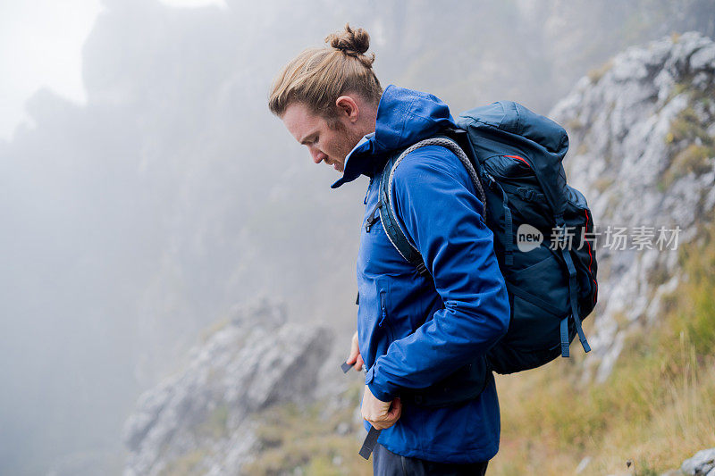 一名男性徒步旅行者在长满草的山脊上休息