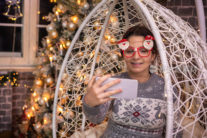 十几岁的女孩使用智能手机在一个舒适的圣诞气氛
