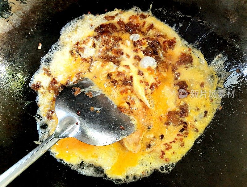用平底锅煮腌萝卜与鸡蛋。
