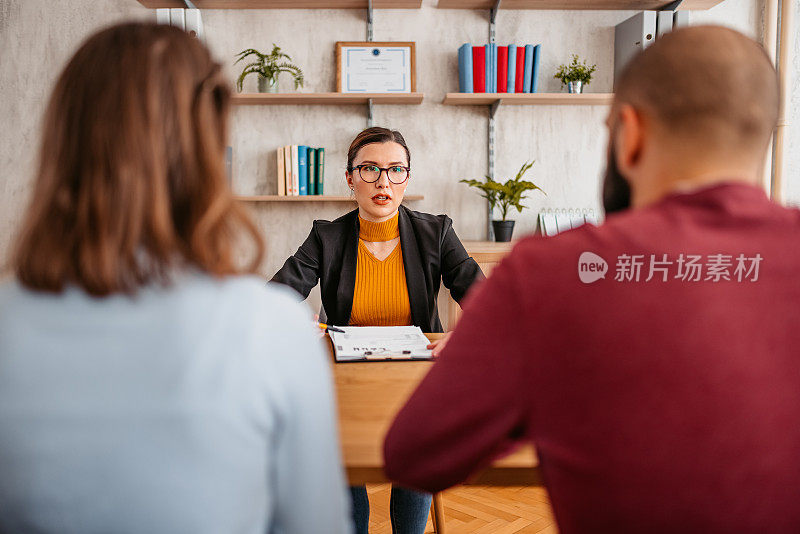 一对年轻夫妇与一位房地产经纪人会面