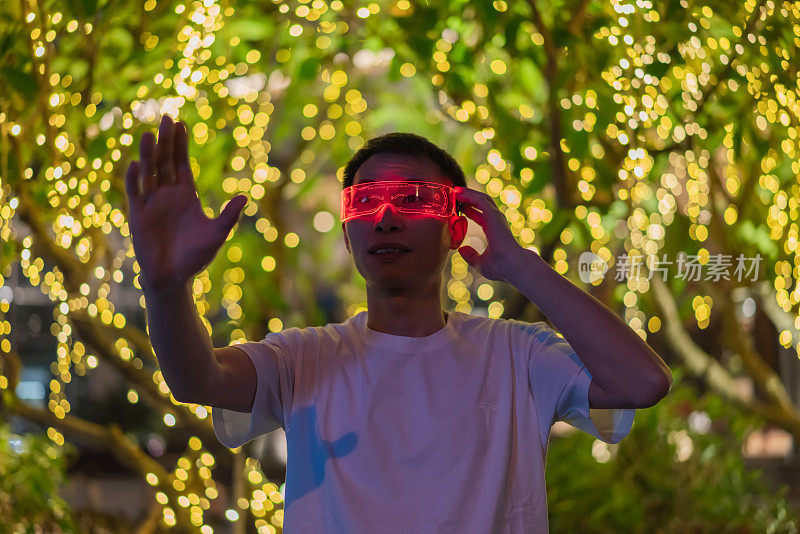 亚洲男性在户外使用增强现实眼镜在夜间体验元宇宙游戏