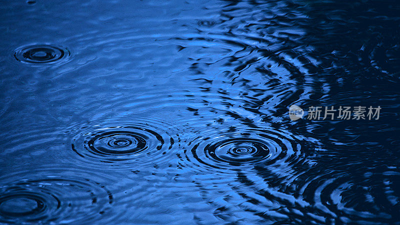 水滴在深蓝色的水坑里泛起涟漪