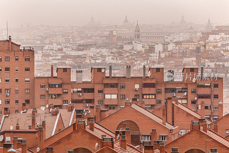 马德里的住宅楼由于撒哈拉沙漠的灰尘而笼罩在橙色的大气中。环境污染和呼吸困难