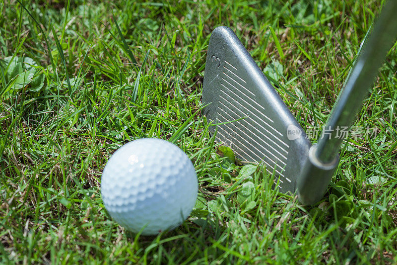 高尔夫球与高尔夫球杆在绿色的草地上，近距离