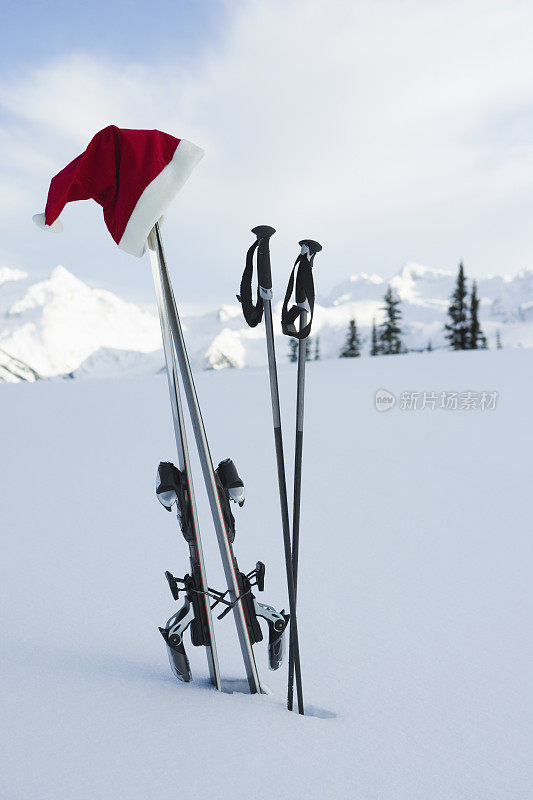 圣诞老人的帽子挂在山上的滑雪板上
