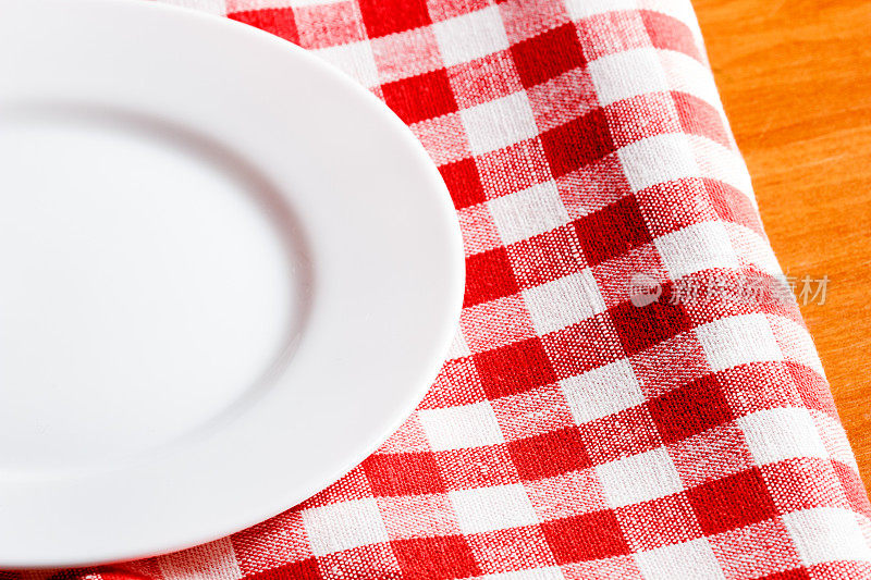 一个空盘子放在红白相间的桌布上