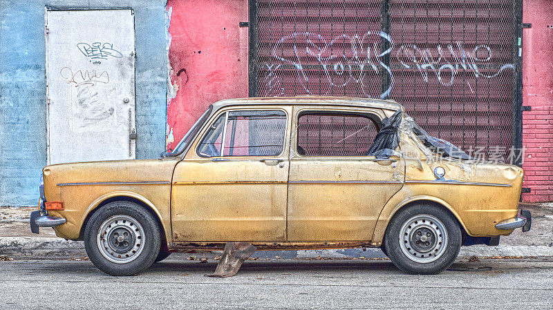 在贫民窟街道上的废弃汽车和涂鸦墙
