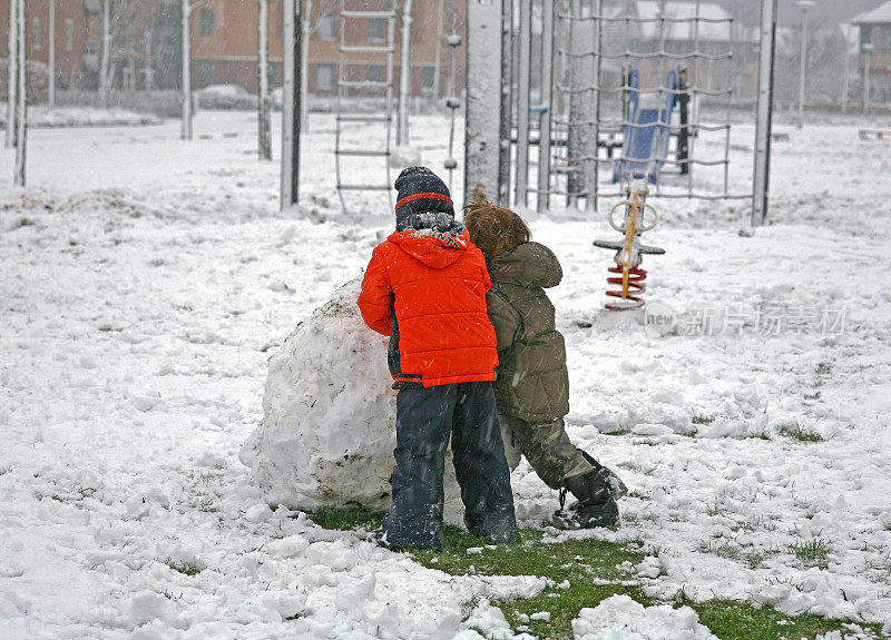 两个孩子正在享受刚下的雪，准备堆雪人