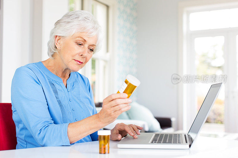 使用笔记本电脑使用药瓶的资深女性。