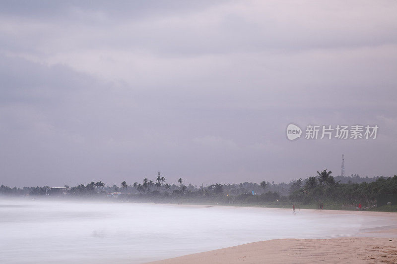 在空旷的斯里兰卡海滩日落上空，雾蒙蒙的戏剧性天空