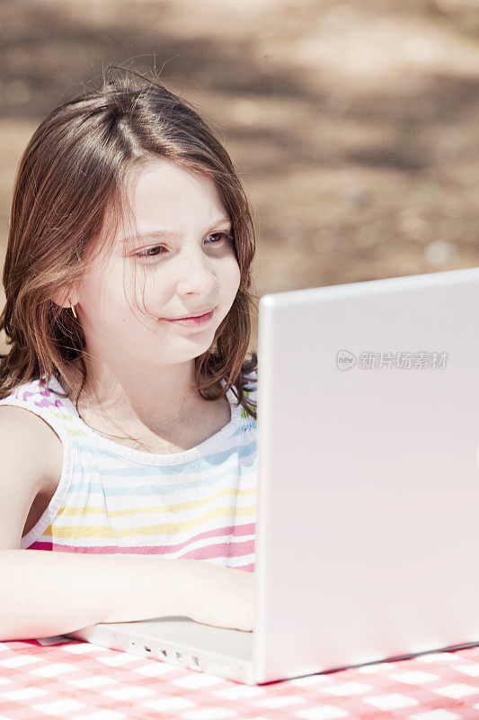 小女孩在户外使用笔记本电脑