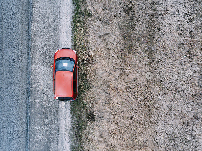 一辆红色的车在春天的乡村路上行驶。