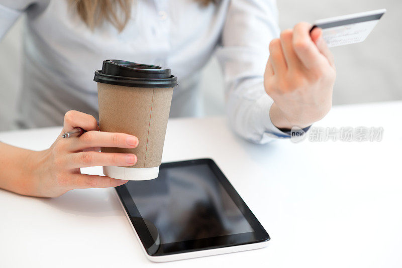 这是一名女商人在早上喝咖啡时使用平板电脑的照片