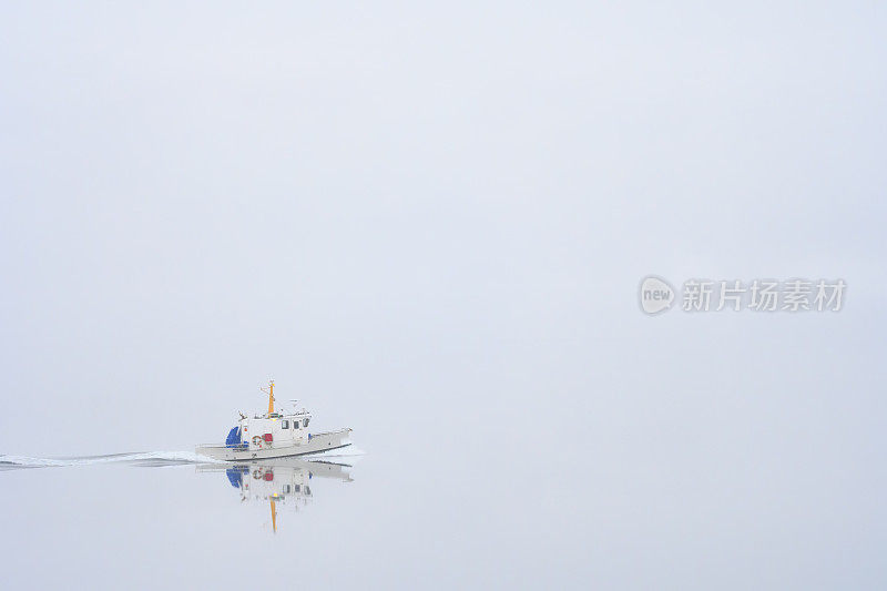 挪威冬天的早晨，在一个多雾的峡湾上的一艘小船