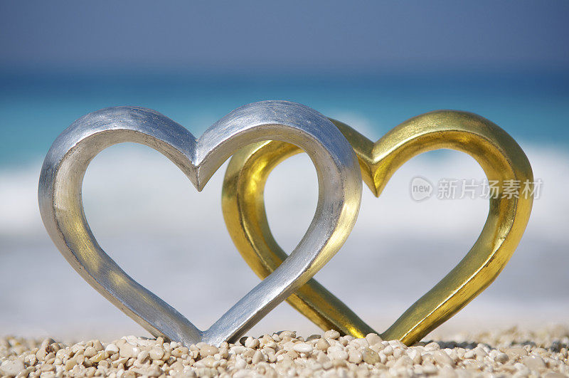 明亮的地中海海滩上的两颗闪亮的心金和银