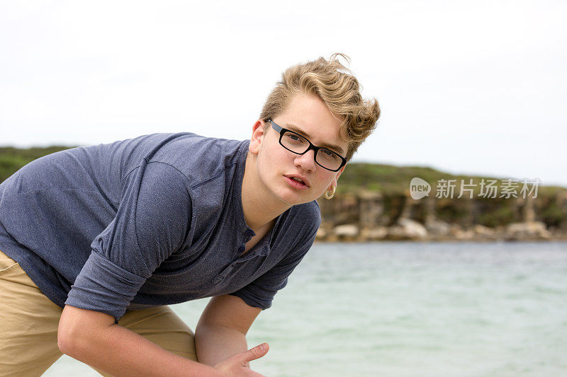 戴眼镜的少年在沙滩上摆姿势，复印区