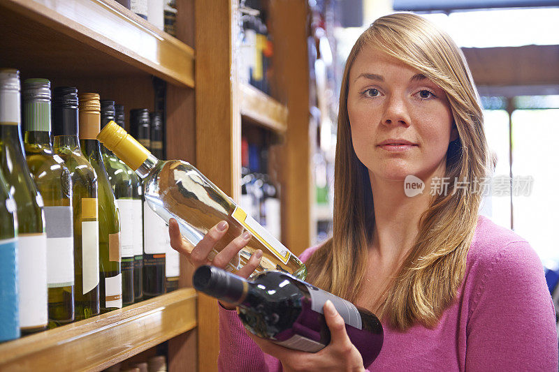 在超市里挑选红葡萄酒和白葡萄酒的女人