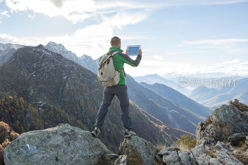 山顶上的徒步者在用平板电脑拍照片
