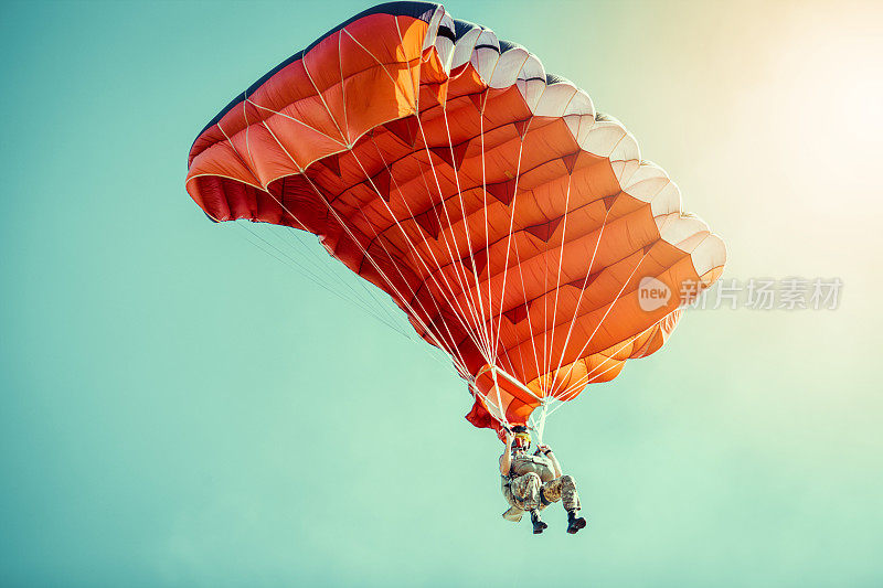 在晴朗晴朗的天空中乘坐彩色降落伞的跳伞者。