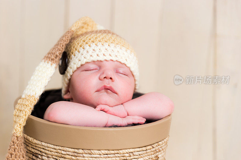 漂亮的睡着的白种新生儿编织羊毛帽子在篮子里