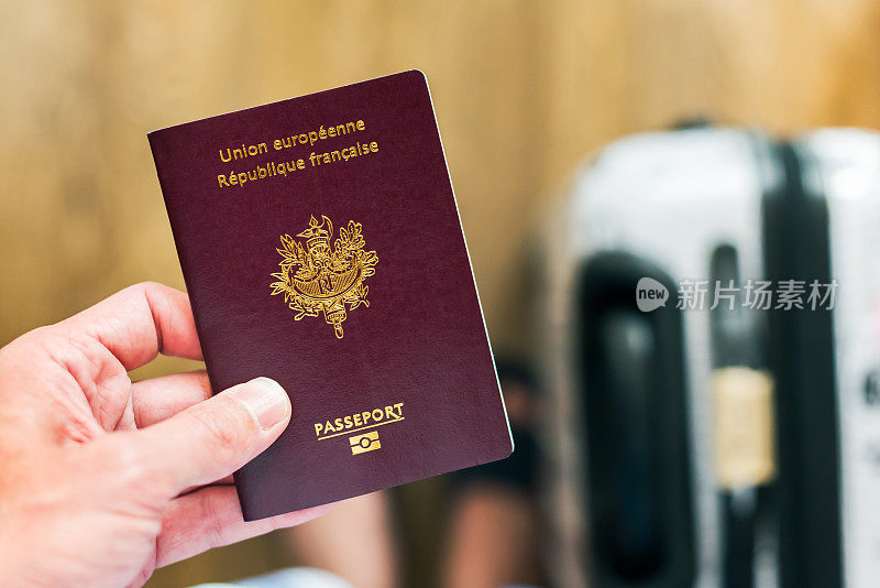手里拿着一本法国-欧洲护照，行李在英国机场