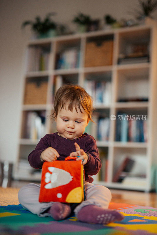 可爱的小女孩玩着婴儿书