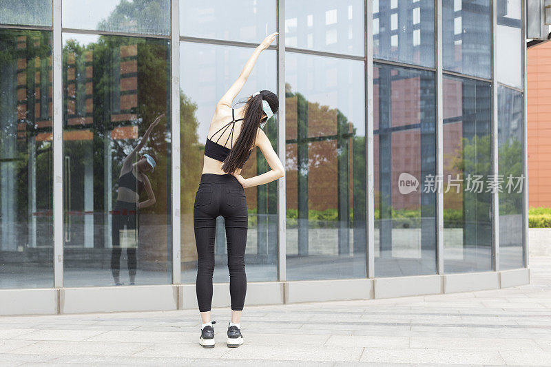 女人在玻璃建筑前做热身