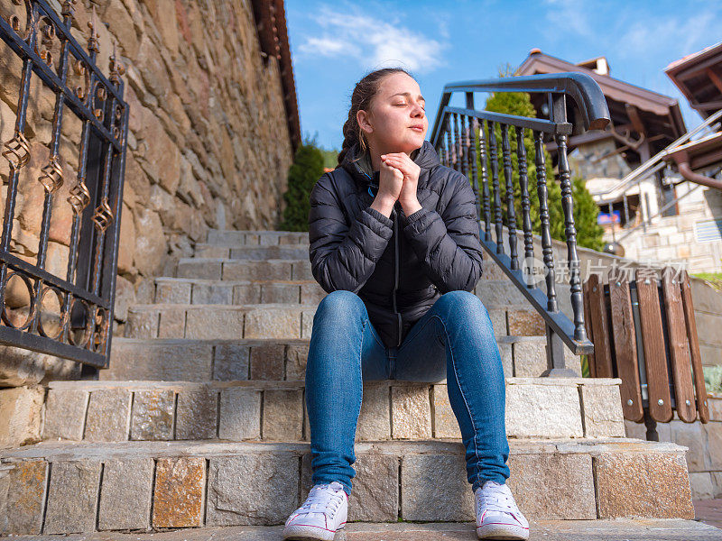 一个女孩坐在户外的石阶上沉思